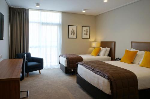 a hotel room with two beds and a chair at The Victoria Hotel Dunedin in Dunedin