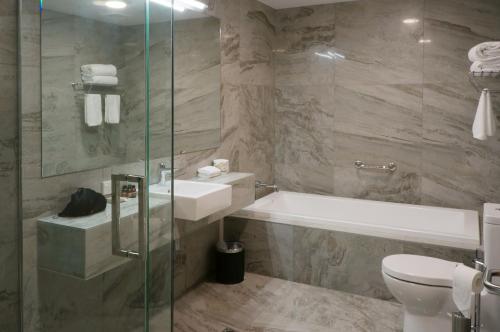 a bathroom with a tub and a sink and a toilet at The Victoria Hotel Dunedin in Dunedin
