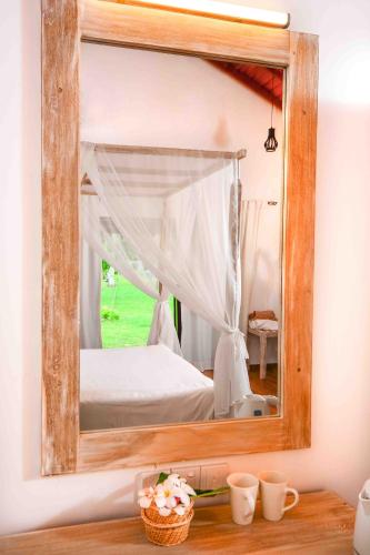 a mirror on a wall with a bed in a room at Handun Villas in Talalla