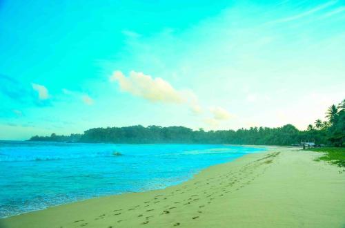 a beach with footprints in the sand and the ocean at Handun Villas in Talalla
