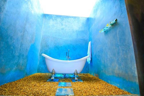 a bathroom with a white bath tub in a blue wall at Handun Villas in Talalla