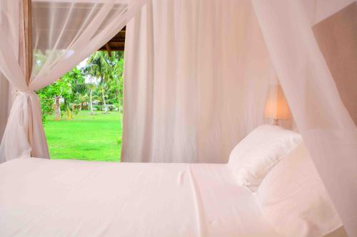 a bedroom with a white bed with a window at Handun Villas in Talalla
