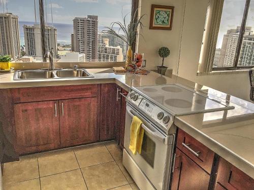 a kitchen with a sink and a stove at Hawaiian Monarch Penthouse 401 by Hawaii Ocean Club in Honolulu