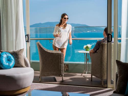 a woman standing on a balcony with a glass of wine at InterContinental Nha Trang by IHG in Nha Trang