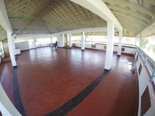 a large room with a red floor and white columns at Sapphire Club Cherai Beach Villa in Cherai Beach
