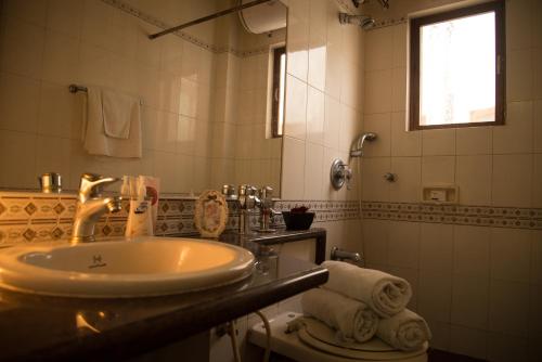 a bathroom with a sink and a toilet and a mirror at Hermitage Suites Koregaon Park Garden & Terrace Room in Pune