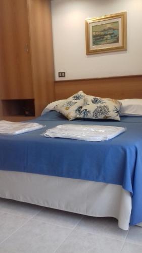 a bed with a blue blanket and pillows on it at Villa Laura Residence Hotel Apartments & Studios in Ascea