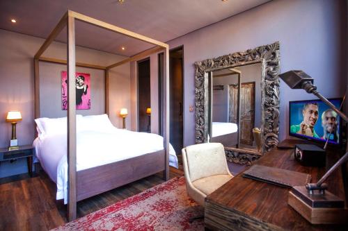 a bedroom with a bed and a desk and a mirror at The Grey Hotel in Cape Town