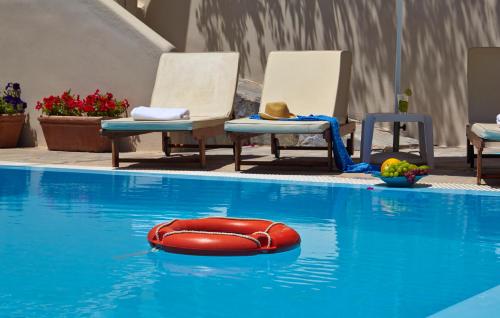 a swimming pool with a blue chair and a blue surfboard at Studios Marios in Kamari