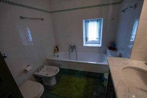 y baño con bañera, aseo y lavamanos. en Coriana Apartments & Villas, en Mulazzo