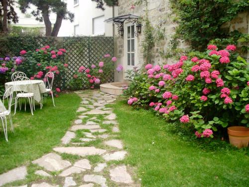 a garden with pink roses and a table and chairs at Villa Escudier Appart-hôtel in Boulogne-Billancourt