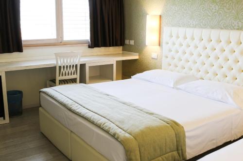 a bedroom with a large white bed and a desk at Nuova Opera Rooms in Verona