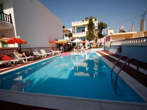 a swimming pool in a hotel with chairs and umbrellas at Eleni Apartments in Hersonissos