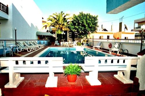 a swimming pool with a white fence and some chairs at Eleni Apartments in Hersonissos