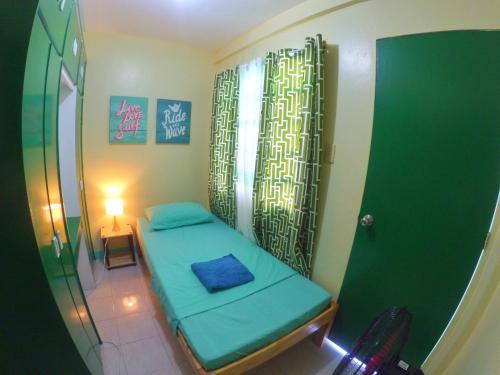 a small room with a green bed and a table at Nomads MNL Backpackers Homestay - near Airport in Manila