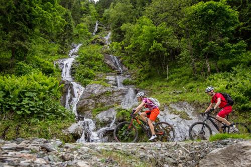 two people riding bikes on a rocky trail near a waterfall at Smaragdhotel Tauernblick in Bramberg am Wildkogel