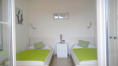 biały pokój z 2 łóżkami i zieloną pościelą w obiekcie Apartment Zea w Novalji