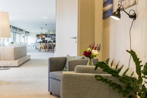 a living room with a couch and a vase of flowers at Familotel Strandkind in Pelzerhaken