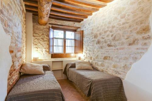 a bedroom with two beds and a stone wall at Umbria Country Shelter in Compignano