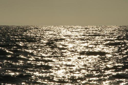 a large body of water with the sun reflecting on it at Familotel Strandkind in Pelzerhaken