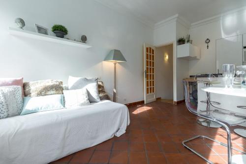 un salon avec un lit blanc et une cuisine dans l'établissement A lovely split level townhouse in the heart of Cannes next to the Marche Forville and the Palais 1749, à Cannes