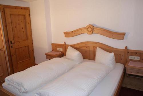 a bedroom with a large bed with white sheets at Singerhof in Fulpmes