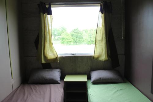 a small room with two beds and a window at Au Bonheur Nomade in Livry