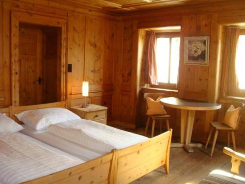 マローヤにあるChesa Alpina, Malojaのベッドルーム1室(ベッド1台、テーブル、椅子付)