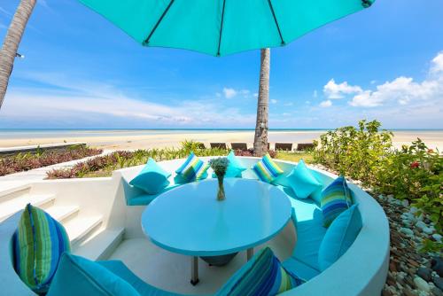 a table and chairs with an umbrella on the beach at Beachfront Villa Baan Paradise in Laem Set Beach