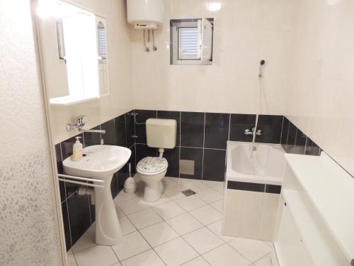 a bathroom with a sink and a toilet and a tub at Apartments Jelena in Pag