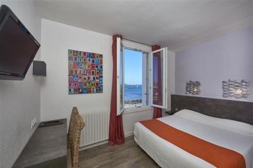 a bedroom with a bed and a window at Logis Hotel Bellevue in Roscoff