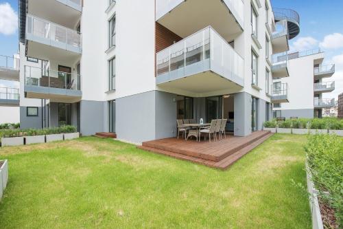an apartment building with a patio and grass at INA Rent - Tre Mare Apartamenty in Gdańsk