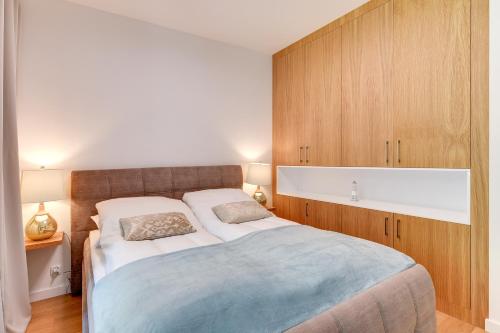 a bedroom with a large bed and wooden cabinets at INA Rent - Tre Mare Apartamenty in Gdańsk