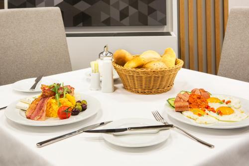 a table with two plates of food and a basket of bread at Hotel Orasac in Belgrade