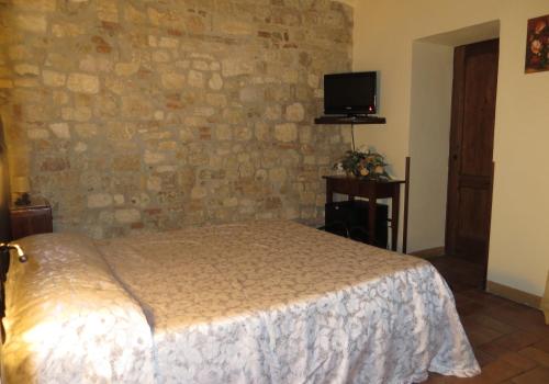 a bedroom with a bed and a stone wall at Agriturismo Casale delle Lucrezie in Todi