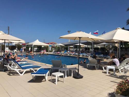 a pool with chairs and umbrellas and people sitting around it at Mariandy Hotel in Larnaka