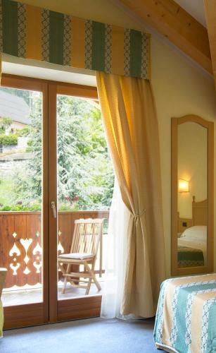 a bedroom with a balcony with a bed and a window at Hotel Du Lac in Molveno