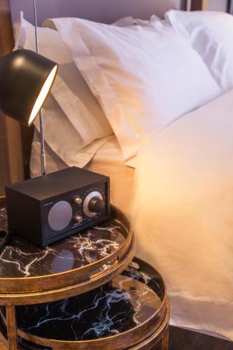 a nightstand with a radio on a table next to a bed at The Grey Hotel in Cape Town