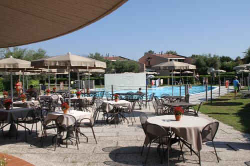 eine Gruppe von Tischen und Stühlen neben einem Pool in der Unterkunft Villaggio Barbara in Moniga