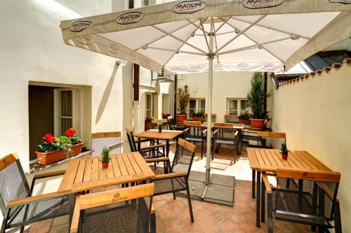 een patio met houten tafels en stoelen en een parasol bij Red Lion Hotel in Praag