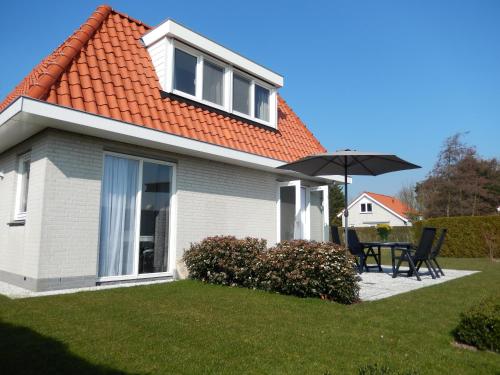 a house with an orange roof with a table and an umbrella at Noordwijk Holiday Rentals in Noordwijk