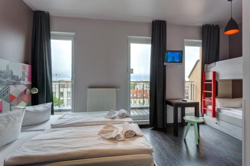 a hotel room with two beds and a balcony at MEININGER Hotel Berlin Alexanderplatz in Berlin