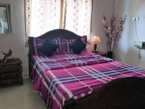 a bedroom with a large bed with a purple comforter at 1 BHK Deluxe Apartment in Candolim by GR Stays in Candolim