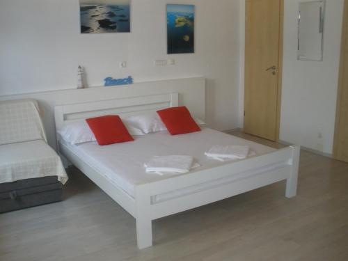 a white bed with two red pillows on it at Apartment Gogi in Vodice