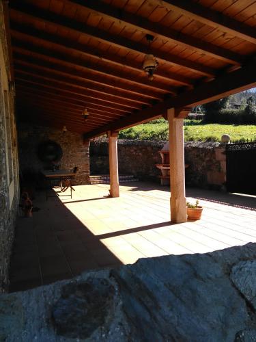 a patio with a wooden roof with a table on it at Casa Rural Oza dos Ríos in Oza dos Ríos