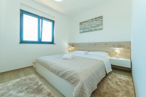 a white bedroom with a bed and a window at Luxury Apartments VilaMaloca in Vir