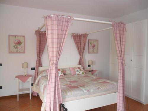 una camera con letto a baldacchino e tende rosa di Ca' Borgo delle Rane a Pernumia