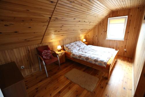 a bedroom in a log cabin with a bed and a chair at Agroturystyka Pod Pstrągiem in Lipnica