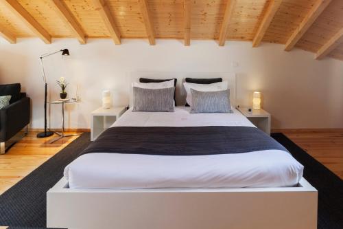 a large white bed in a room with wooden ceilings at BO - Almada in Porto