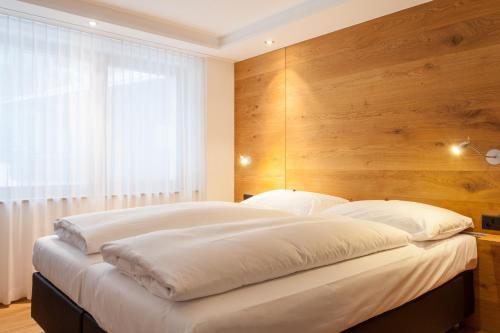 a bedroom with a large bed with a wooden wall at Elite Alpine Lodge - Apart & Breakfast in Saas-Fee